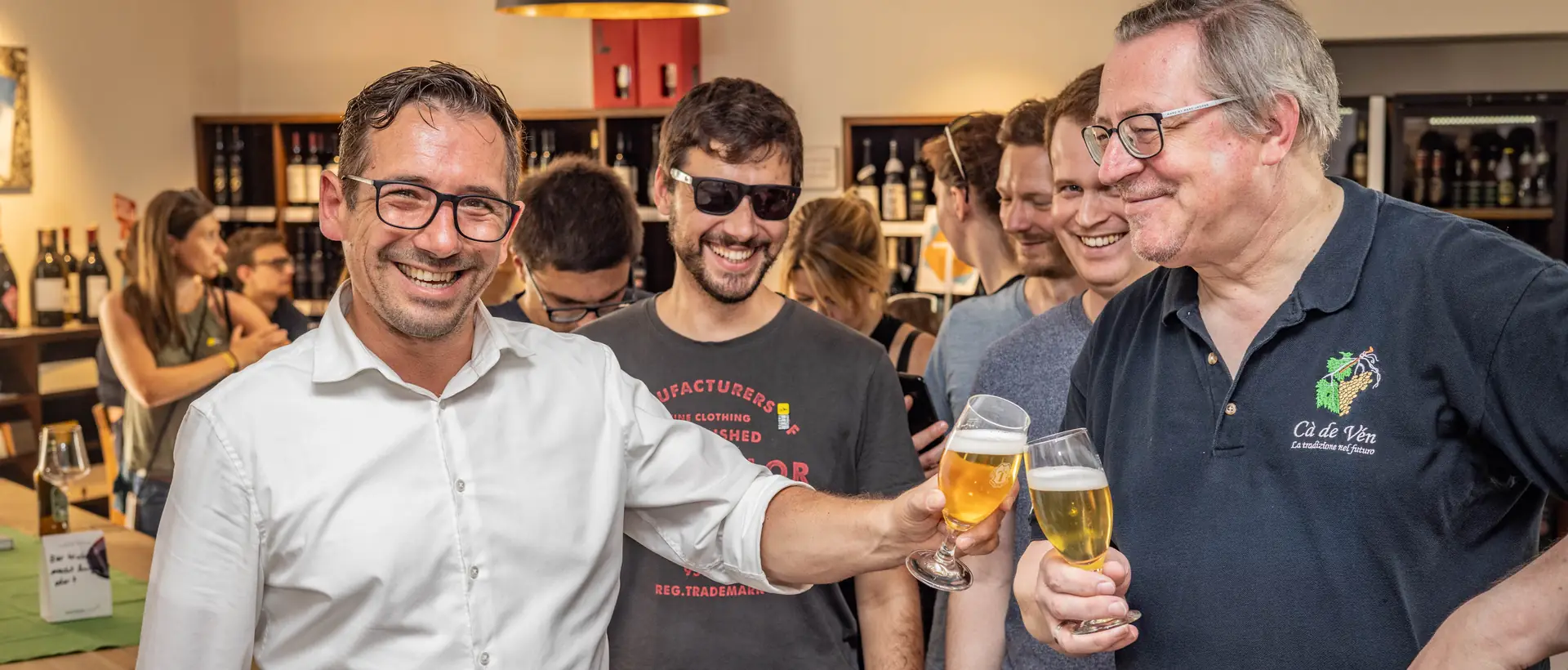 Lachende Gruppe stößt bei einer Bierverkostung mit Gläsern an